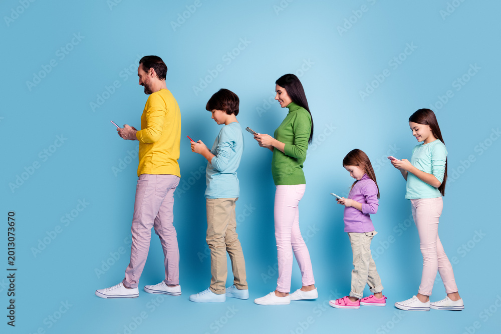 Fototapeta premium Family walking in line using smartphones, parents and children absorbed in mobile screens, modern digital lifestyle and generational tech habits on a blue background