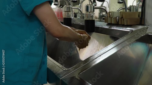 Surgeon washing hands thoroughly at sink before sterile procedure in modern operating theater