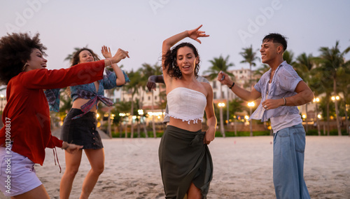 A diverse group of multicultural friends enjoying summer moments on the beach, dancing, laughing