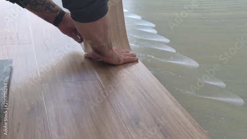 Close up of a professional flooring installer placing a self-adhesive vinyl plank onto the floor.