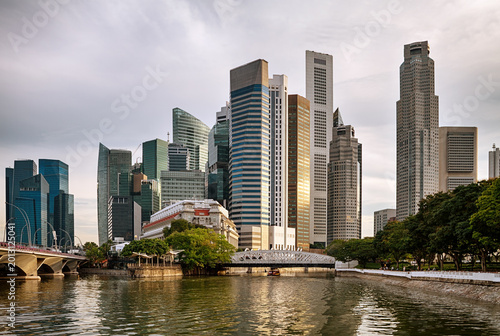Obraz na płótnie Modern city skyline with tall skyscrapers, river reflections, and urban waterfront architecture in Singapore during soft evening light