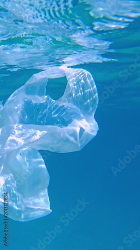 A plastic bag floats in the water, illustrating pollution and environmental damage. The clear bag contrasts with the blue water, highlighting the issue of garbage in aquatic environments.