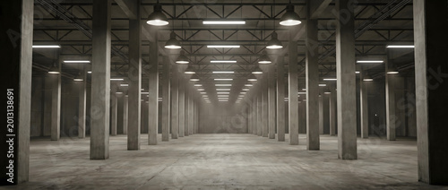 Empty industrial warehouse with concrete columns forming a long symmetrical corridor under overhead lighting
