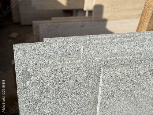 Granite slabs with speckled pattern stacked in sunlight, ideal for construction background