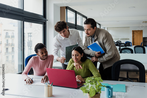 multiethnic Group of young people in a meeting and working at office. Diverse hispanic teamwork using laptop at workplace