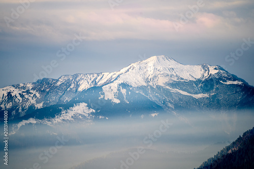 Majestic grass covered Himalayan peaks rising above misty valleys in Himachal Pradesh, showcasing serene mountain landscapes and natural beauty.