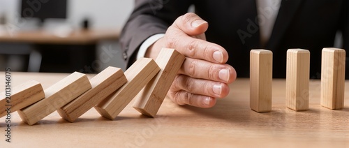 Hand stopping falling wooden blocks to prevent chain reaction on table