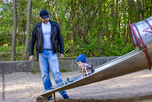 Father with toddler son on play ground having fun