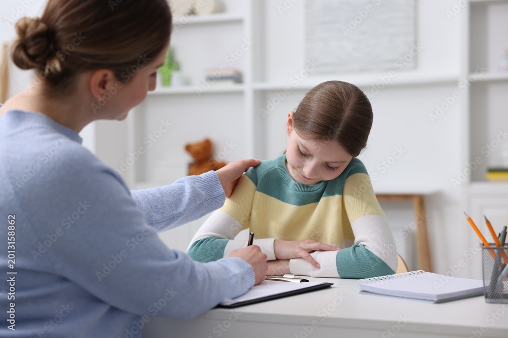 Obraz premium Professional child psychologist working with girl at white table indoors