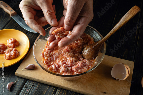 Photos A person shapes a mixture of ground meat in a bowl using hands