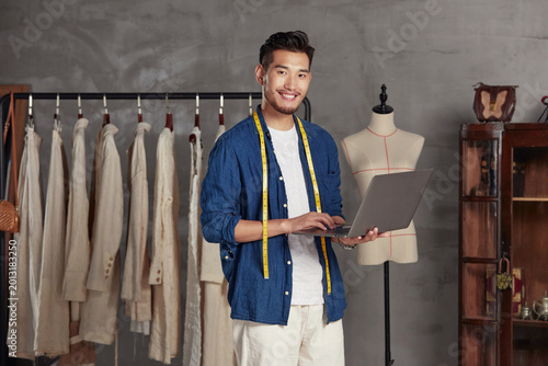 Foto Tailor using laptop in clothing studio
