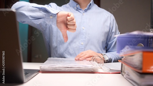 Fényképezés Office worker at desk giving a thumbs down gesture to express rejection, disappr