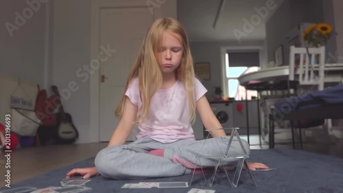 A girl carefully and patiently building a card house. The cards fall down. She gets upset. Game concentration attention focus. 