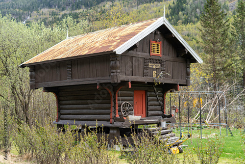 Authentic traditional Norwegian stabbur (raised wooden storehouse) in the rural landscape of Telemark, Norway. Historic dark timber architecture.