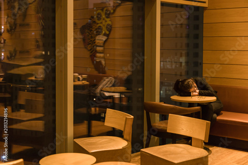 Fotografie Young Woman Sleeping Alone in Cafe at Night