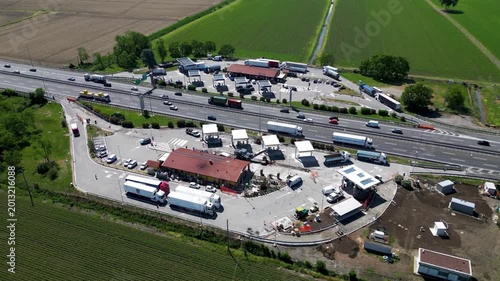 Highway Rest Stop Panorama: An aerial view showcases a bustling highway rest stop, complete with fuel stations, dining facilities, and ample parking for trucks and cars.