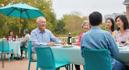Multigenerational family enjoying an outdoor communal meal with turquoise chairs for garden party background and celebration banner design