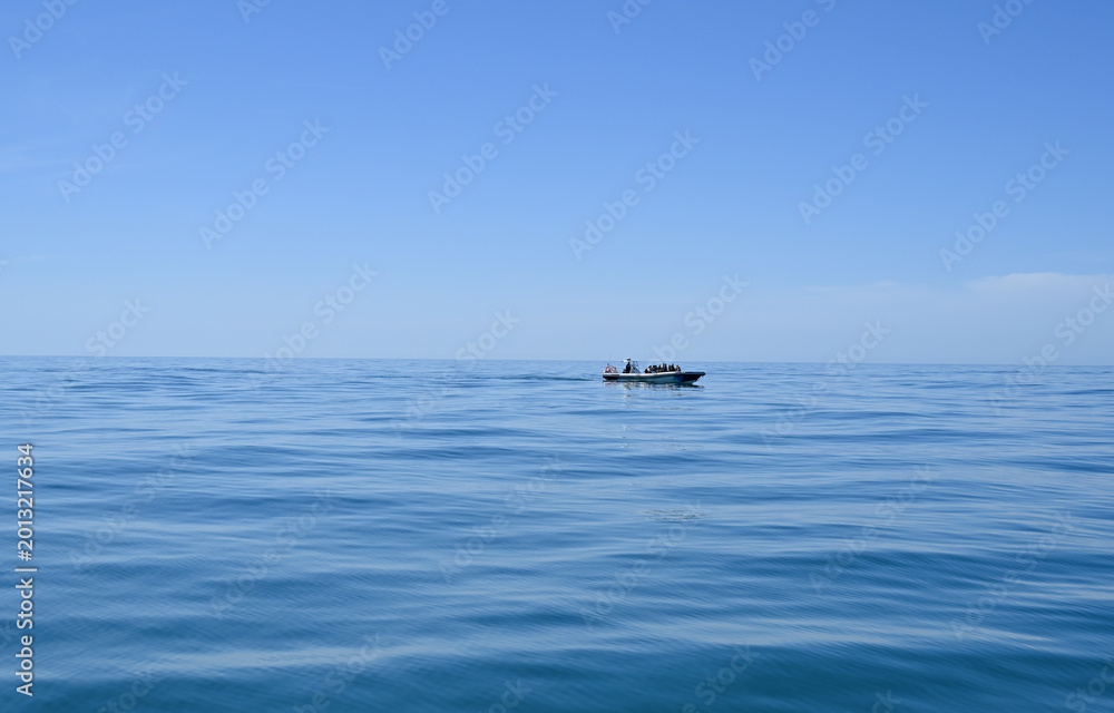 Fototapeta premium Small Motorboat with Passengers Cruising on Calm Blue Ocean Water