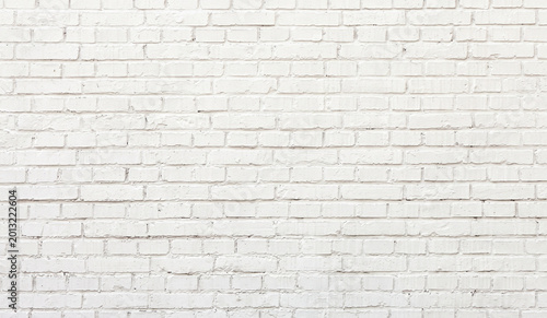 A textured white brick wall with a uniform appearance. The bricks are arranged in a traditional pattern, giving the wall a clean and minimalistic look.