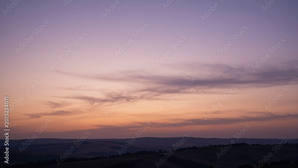 Fototapeta premium Sky displaying layered clouds over rolling hills at sunset