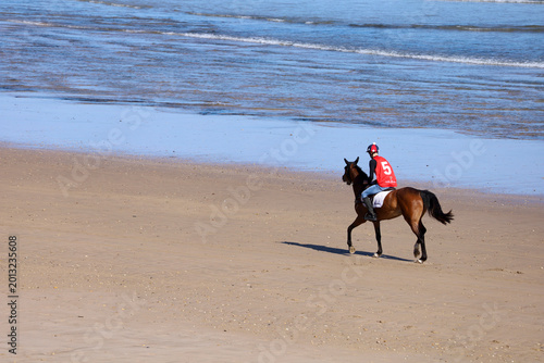 Fotografie Jockey participating in horse race on Santa Marina beach in Ribadesella town