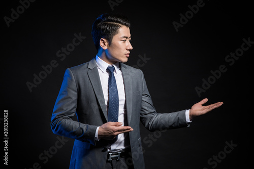 Tableau sur toile Confident businessman presenting with hand gesture