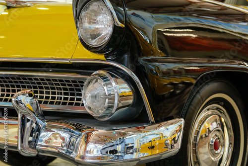 Φωτογραφία Detailed low-angle close-up highlights front of classic vintage car with striking yellow and black color scheme