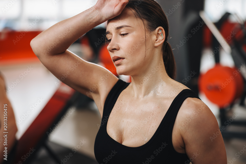 Fototapeta premium Tired woman with sweat on her body training in gym