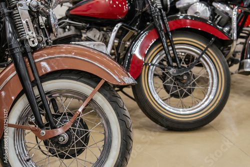 Canvas-taulu Detailed view captures front wheels and fenders of two vintage motorcycles parked indoors