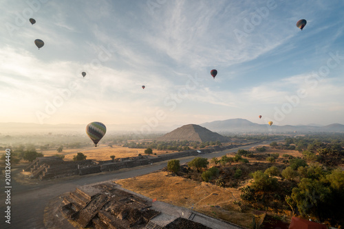 Hot air balloons floating over Teotihuacan pyramids at sunrise in Mexico with scenic landscape and clear sky