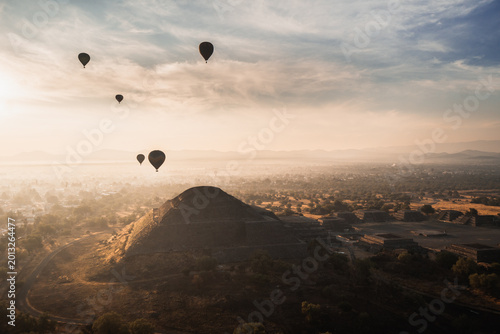Hot air balloons floating over Teotihuacan pyramids at sunrise in Mexico with scenic landscape and ancient architecture