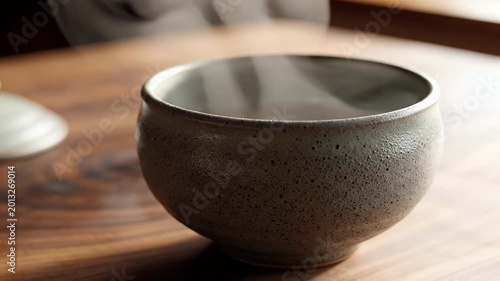 Steaming Ceramic Bowl Sitting on Rustic Wooden Table in Warm Natural Light