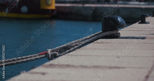 Close up of mooring ropes tied to a dock cleat on a waterfront dock in Rovinj, Croatia.