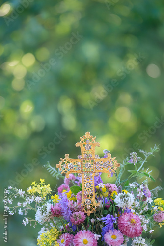 Foto beautiful golden openwork cross with rhinestones and meadow flowers bouquet close up outdoor, nature background