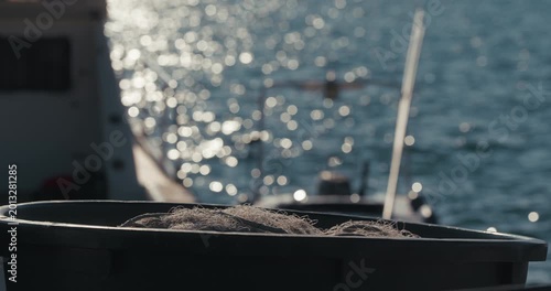 Fishing net inside a container with blurred sea and boat in the background at harbor in Rovinj, Istria, Croatia.