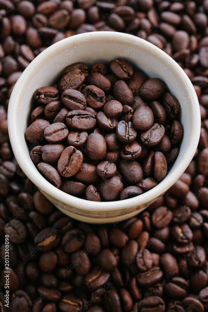 Fototapeta premium Vertical Close Up of Premium Roasted Coffee Beans in White Ceramic Espresso Cup