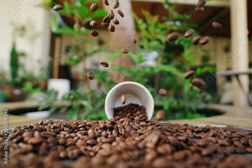 Cinematic Action Shot of Roasted Coffee Beans Falling and Bouncing with Espresso Cup