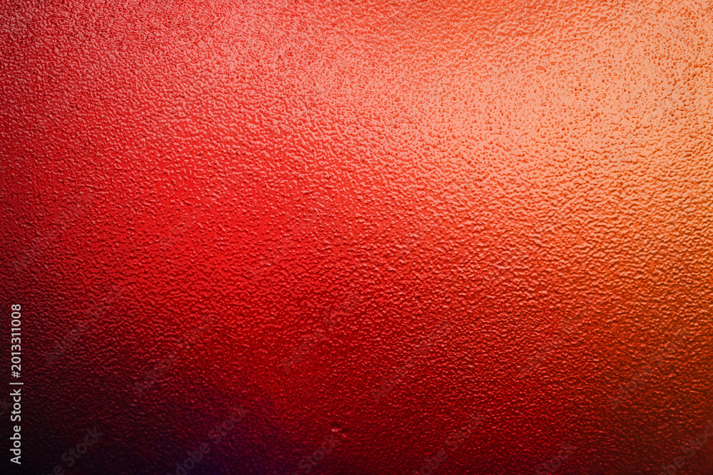 Fototapeta premium Vibrant red and orange illuminated frosted glass texture background with dark gradient