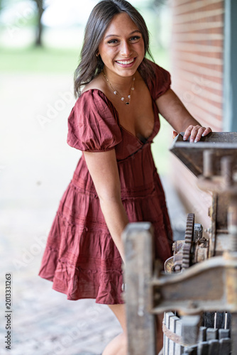 Φωτογραφία Young girl is smiling while pretending to use an old agricultural equipment in W
