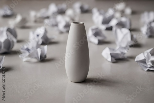 Perfect white ceramic vase standing out among crumpled paper wads concept of a brilliant idea