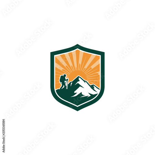 Hiker with backpack ascends mountain peak with sunrays behind