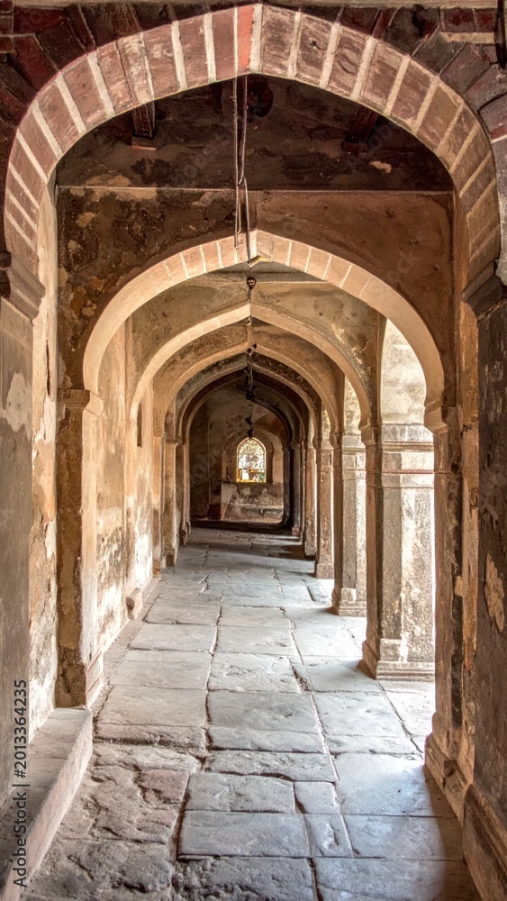 Fototapeta premium Long corridor of arched doorways and walkways, leading to a window at the end