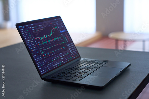 Stock market chart displayed on laptop screen on dark desk