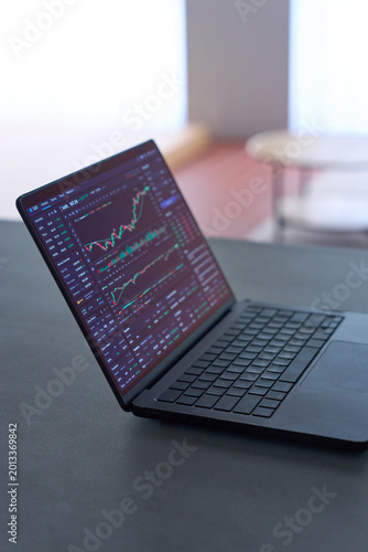 Stock market chart displayed on laptop screen on dark desk