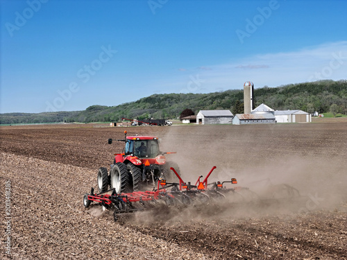 Foto Red tractor  Pulling a  Double Fold Cultivator for spring field preparation