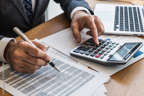 Close-up of hands calculating with calculator and papers