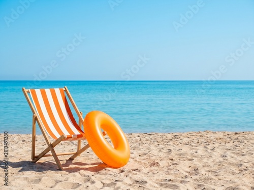 Beach chair and swim ring on sandy shore