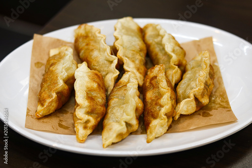 Several golden-brown, deep-fried Korean dumplings (Gun-mandu) served on brown parchment paper.