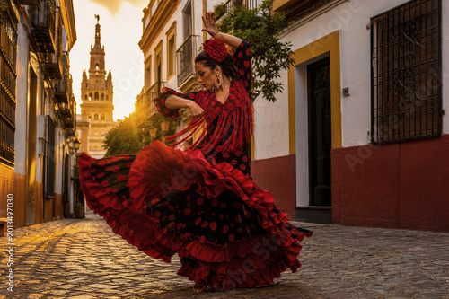 Woman in red dress dancing flamenco on a charming old European street with flowers and historic houses