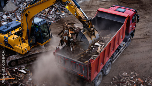 Quadro su tela Excavator loading a dump truck with scrap metal or debris at an industrial construction site